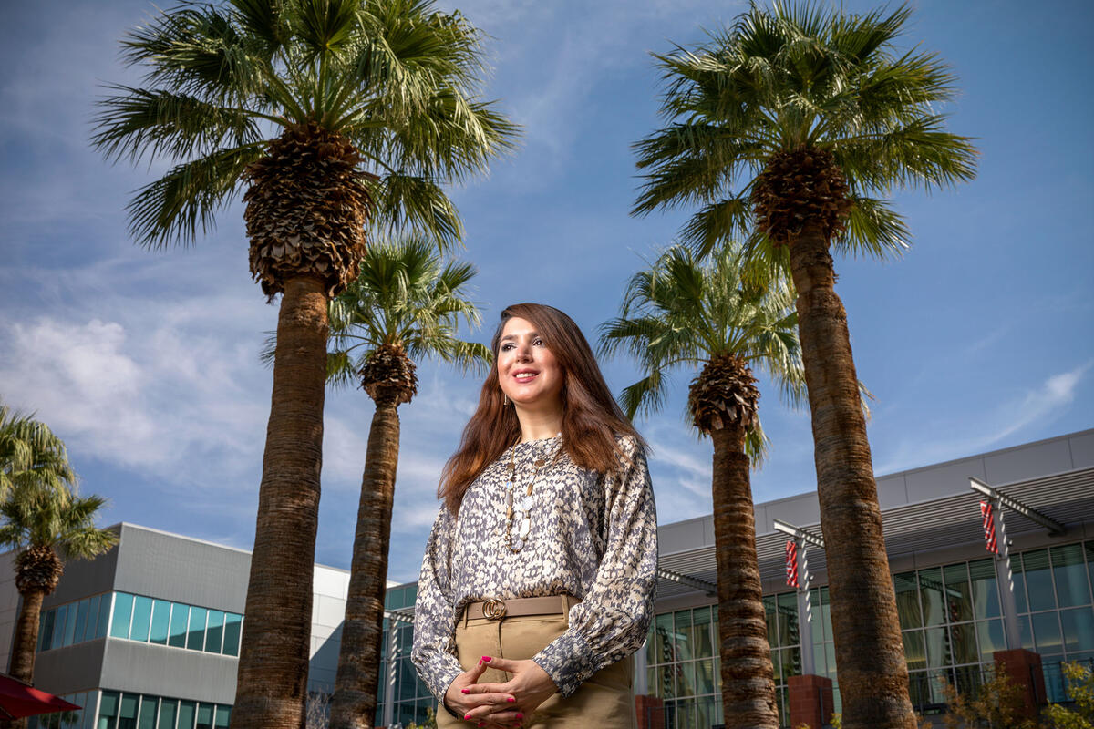 woman posing in front of campus building and palm trees