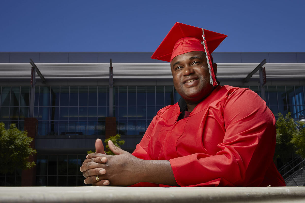 man in graduate cap and gown pictured outdoors
