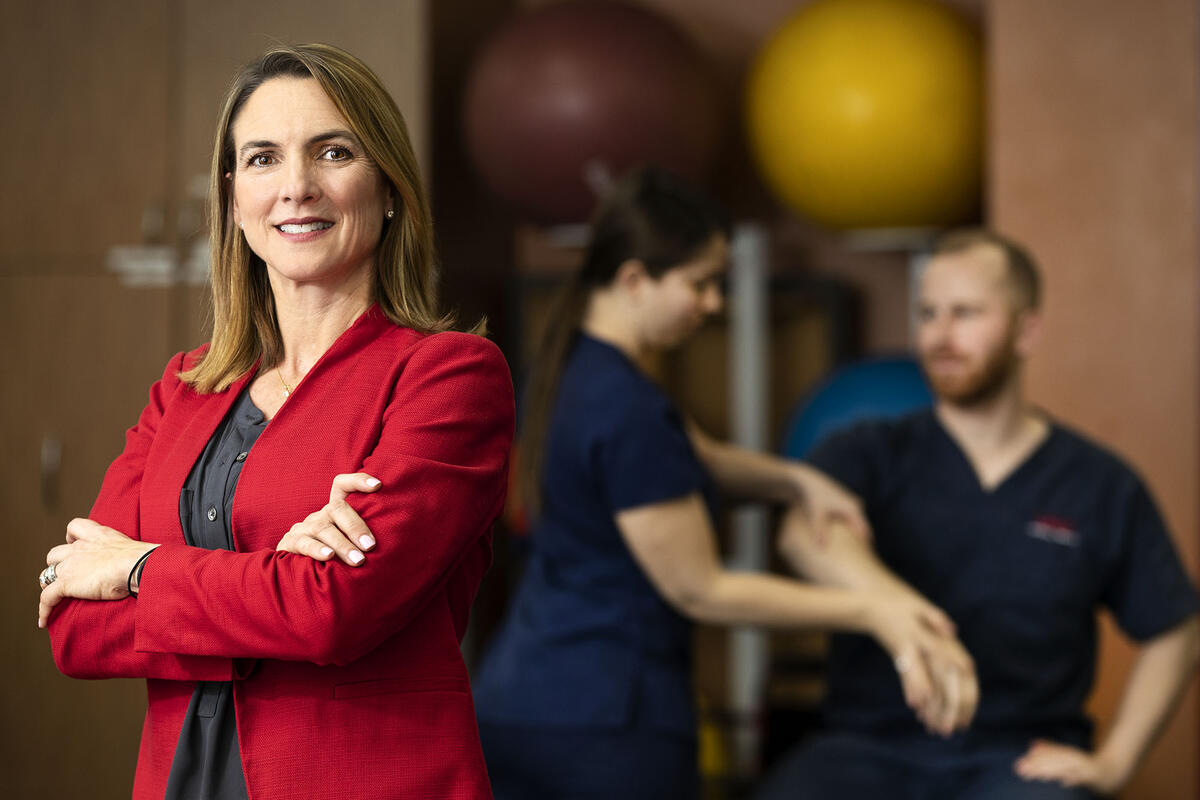 woman posing with two physical therapists working behind her