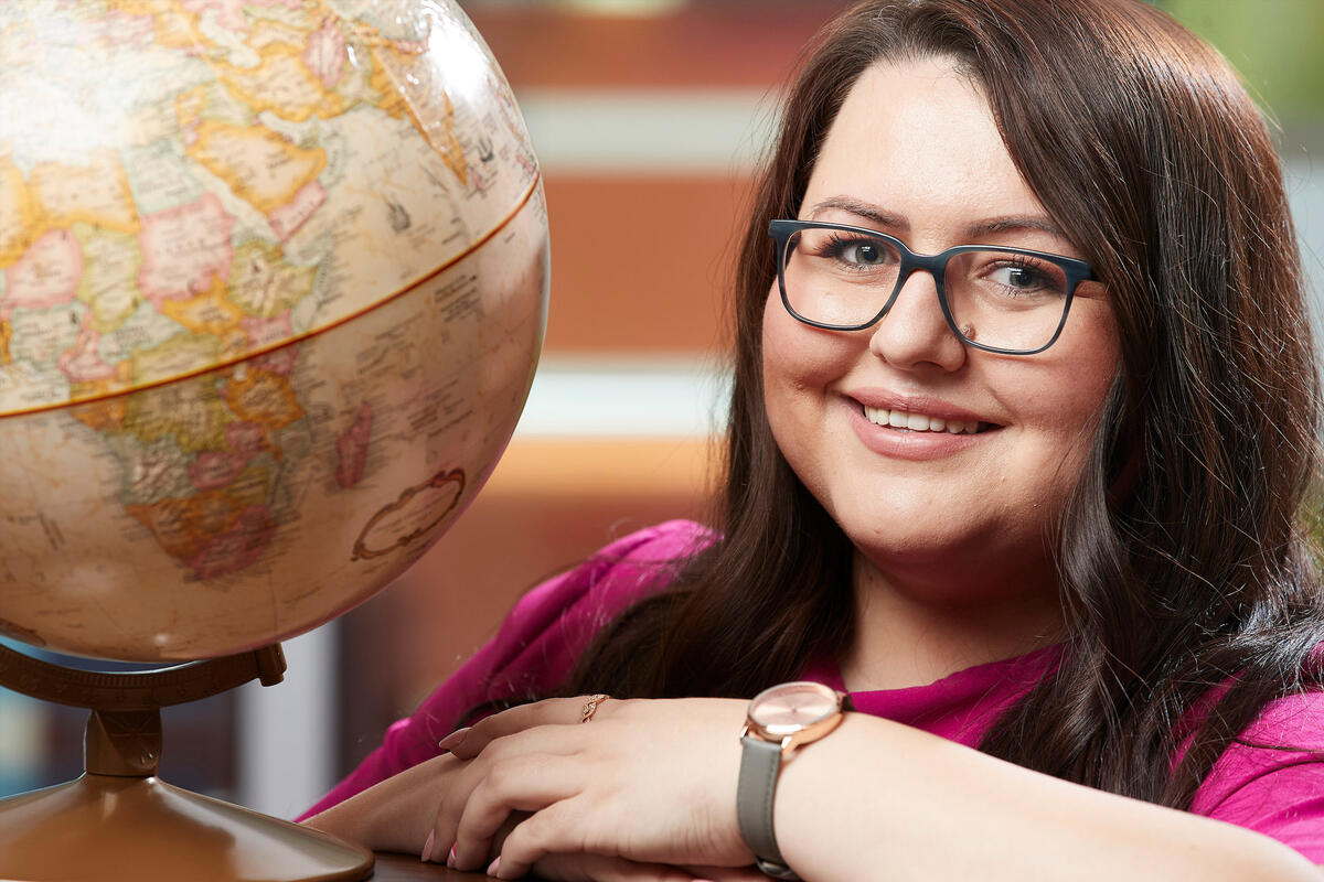 A woman is seated next to a globe