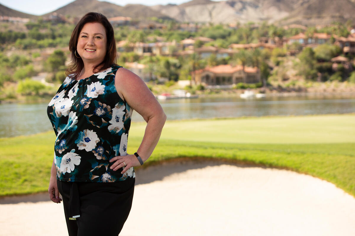 A woman stands at a sand trap on a golf course