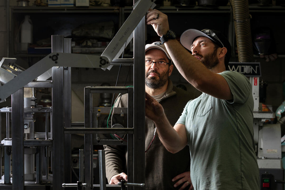 Two students work on a mechanical apparatus