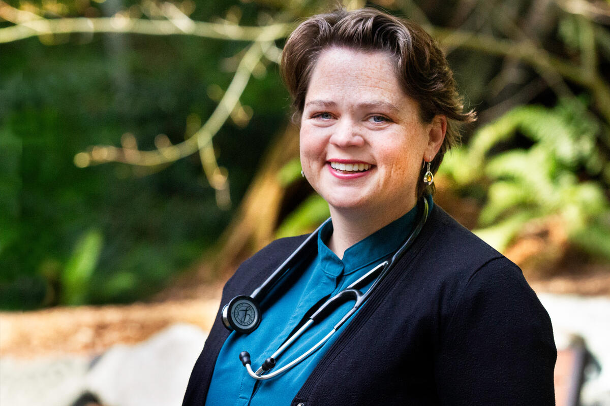 A woman wearing a stethoscope smiles.