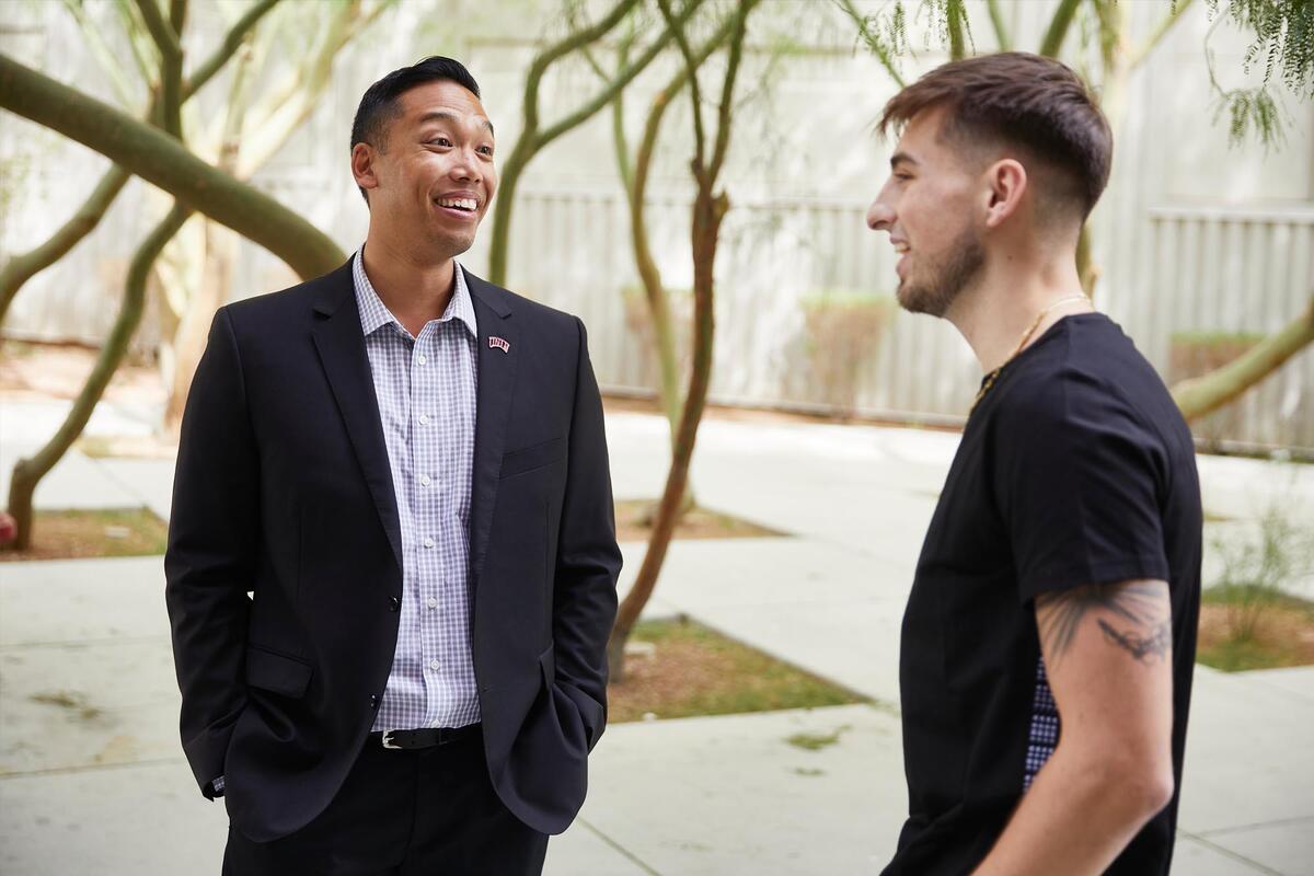 Two men talk in a courtyard