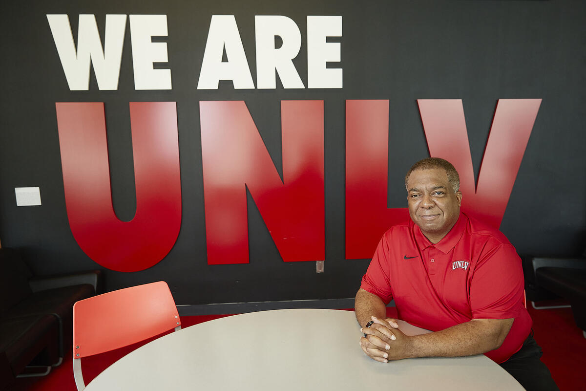 man sitting in front of display wall that says "We Are UNLV"