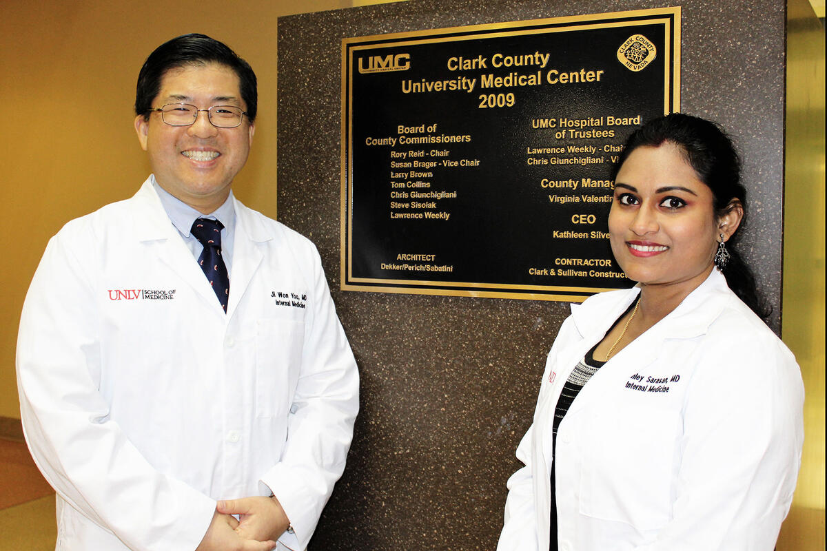 Drs. Ji Won Yoo and Ashley Sarasan pose in front of a plaque.