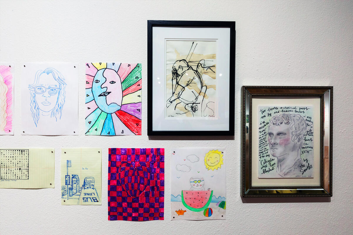 Several drawings hang on a wall