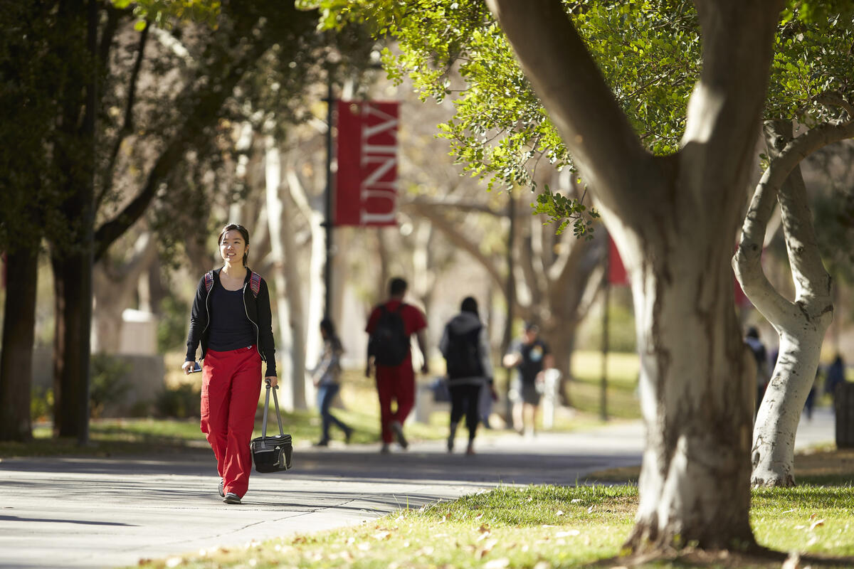 Female student walking on campus during a sunny day.