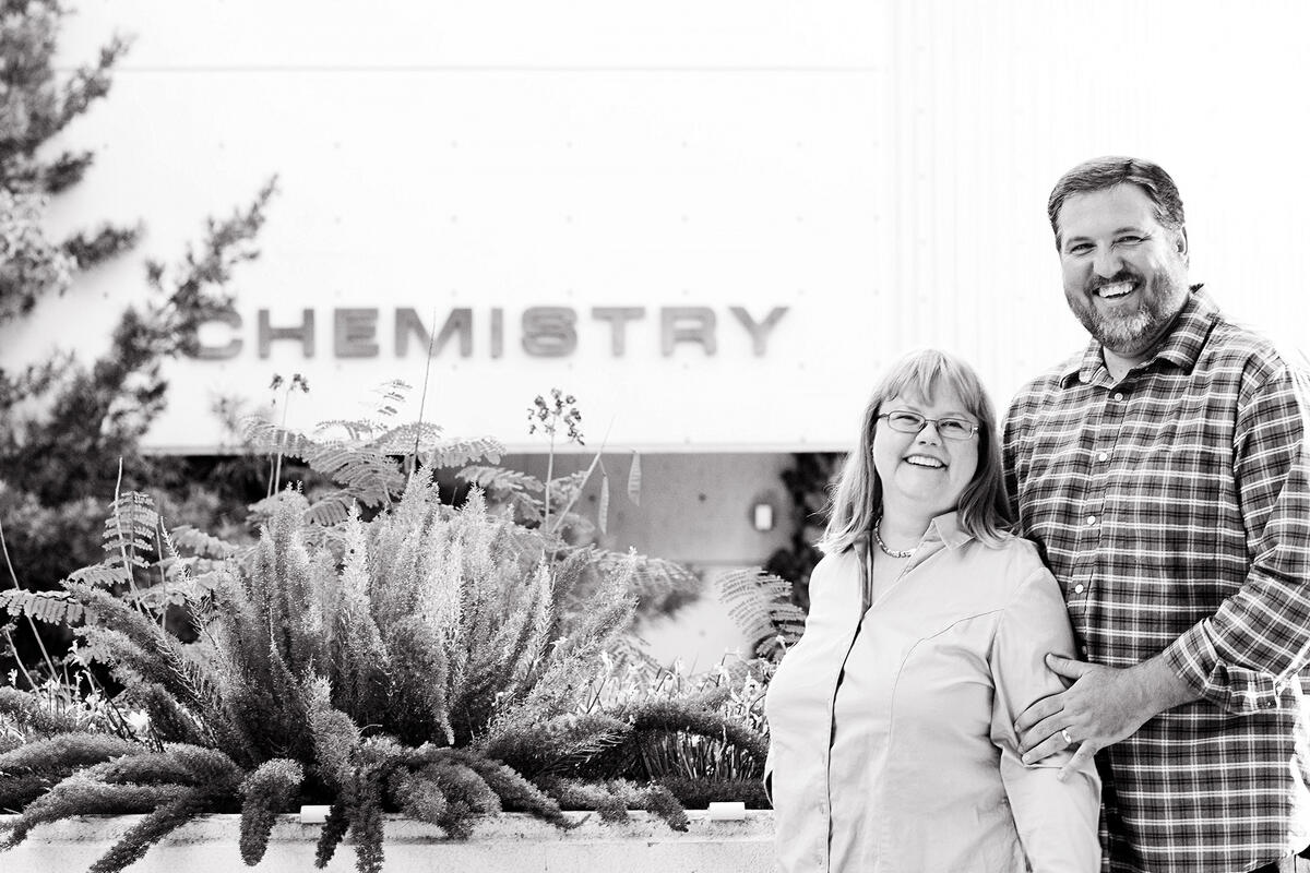 a woman and man stand near a cactus outside the chemistry building