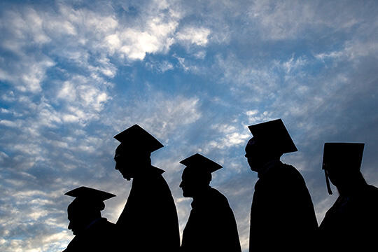 Silhouettes of people in graduation cap and gown  