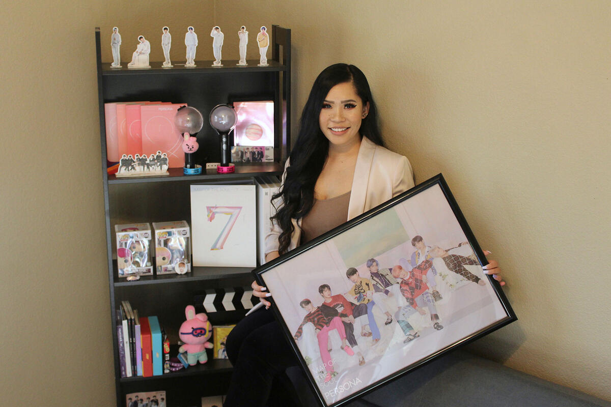 Nicole Santero at home, surrounded by BTS memorabilia, including a poster.