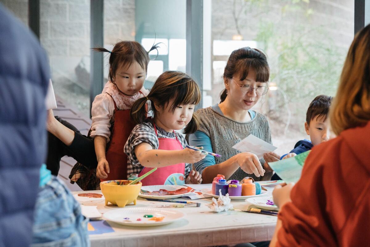 An adult and kids working on art