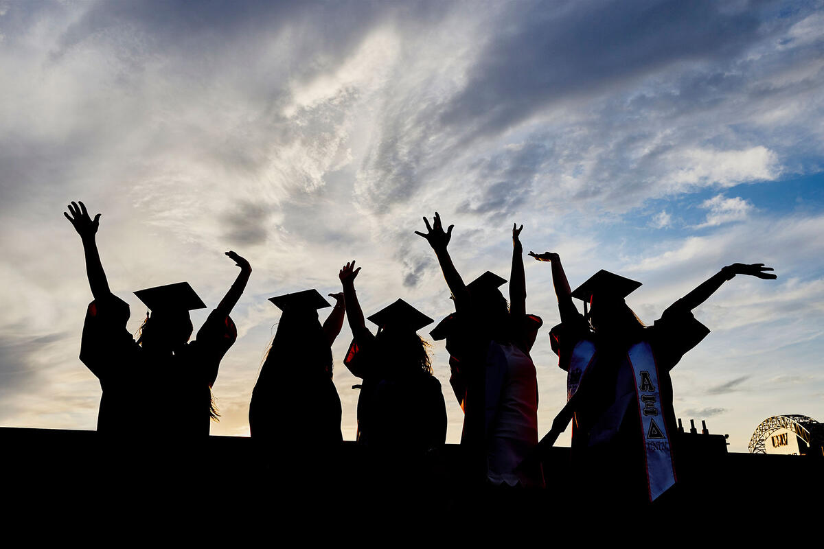 A group of graduates with their arms in the air
