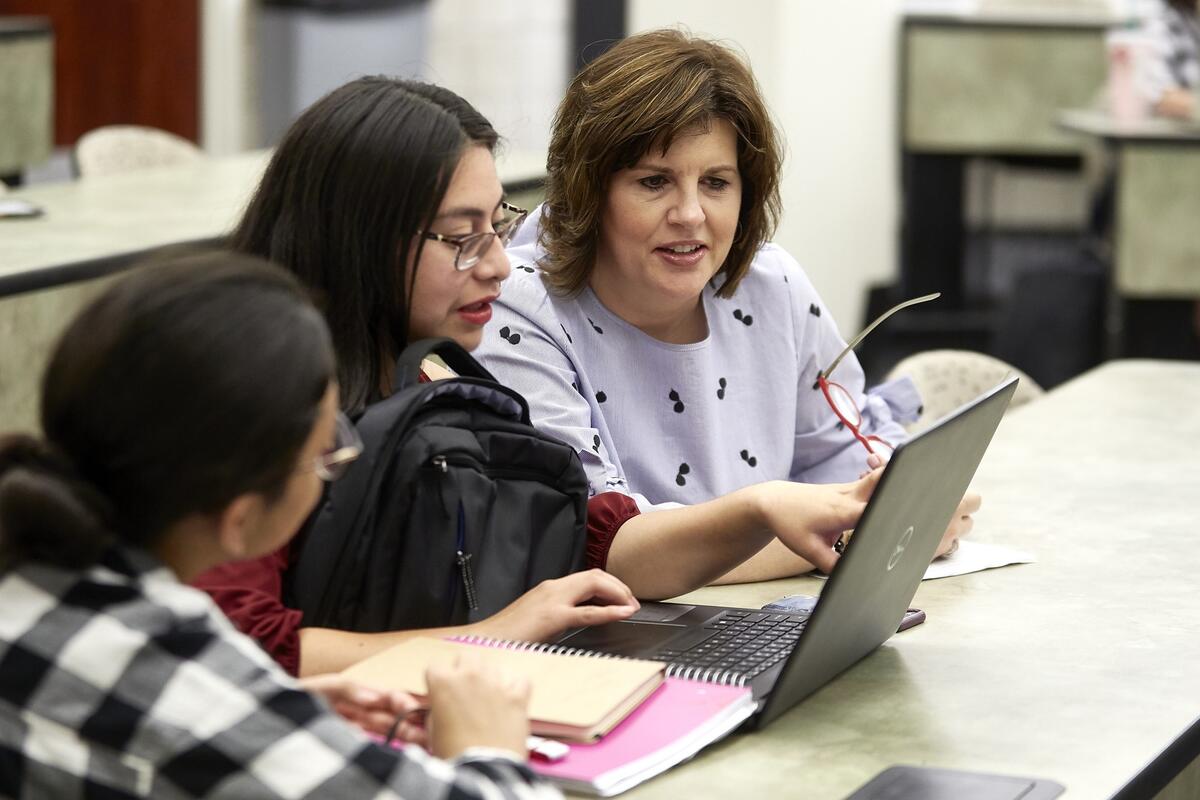 Women helping students with laptop
