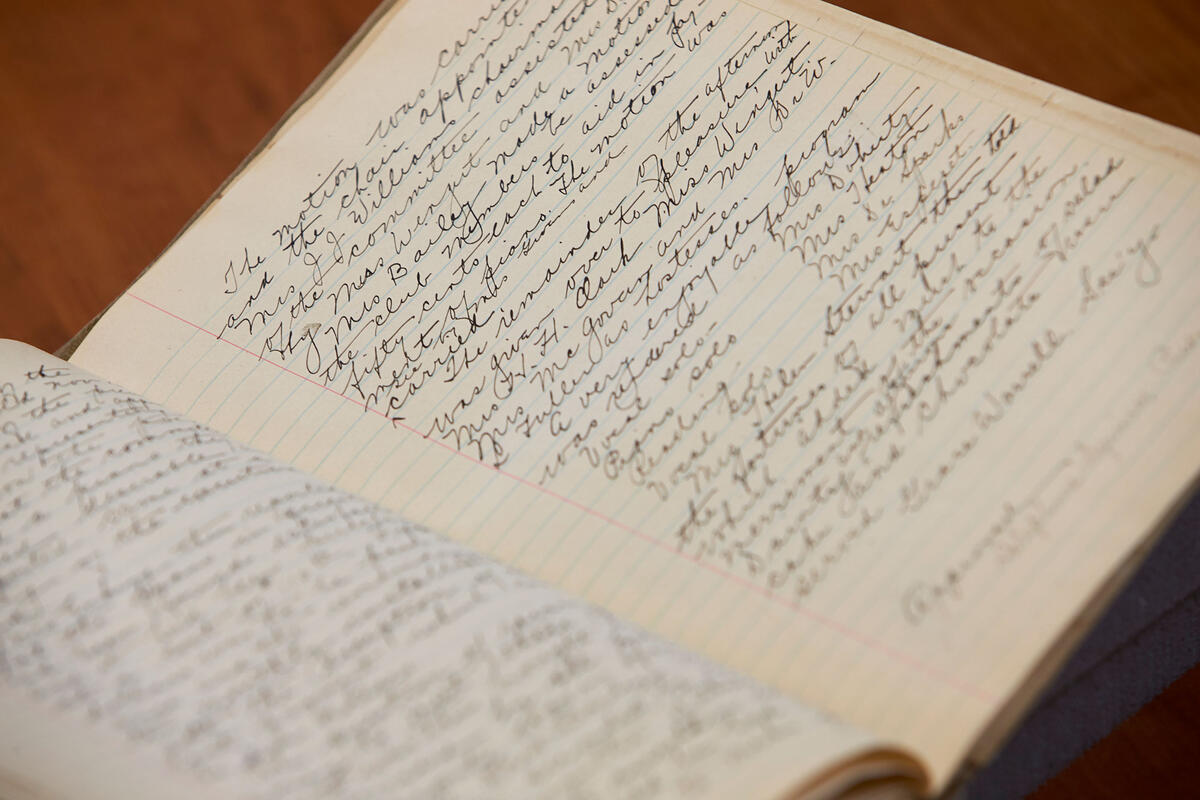 An open journal with hand-written cursive displayed on a wooden table