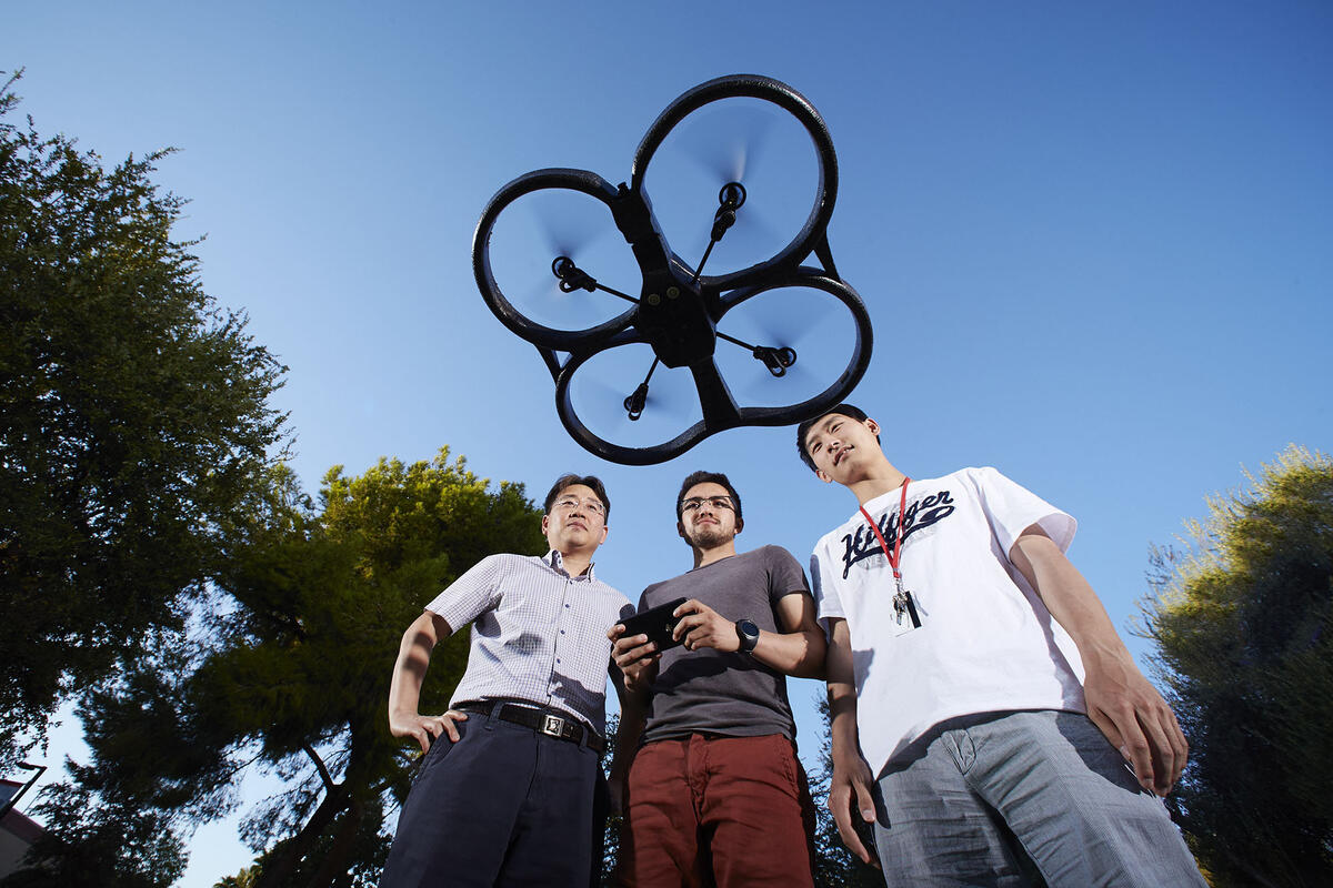 Three males flying a drone in the air