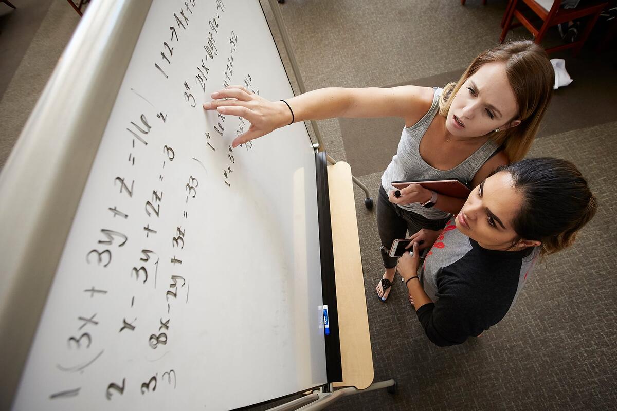 Two women working on a large math equation together.
