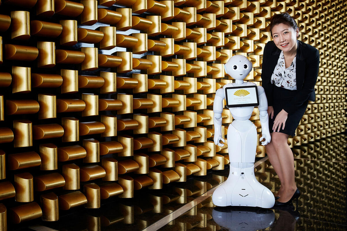 A woman standing next to a robot