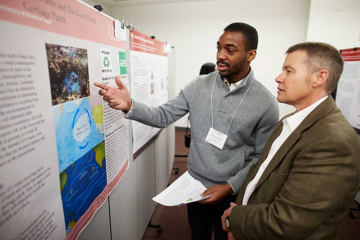 Two people converse while looking at research posters