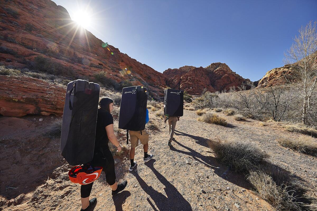 Climbers with their crash pads hiking towards boulders.