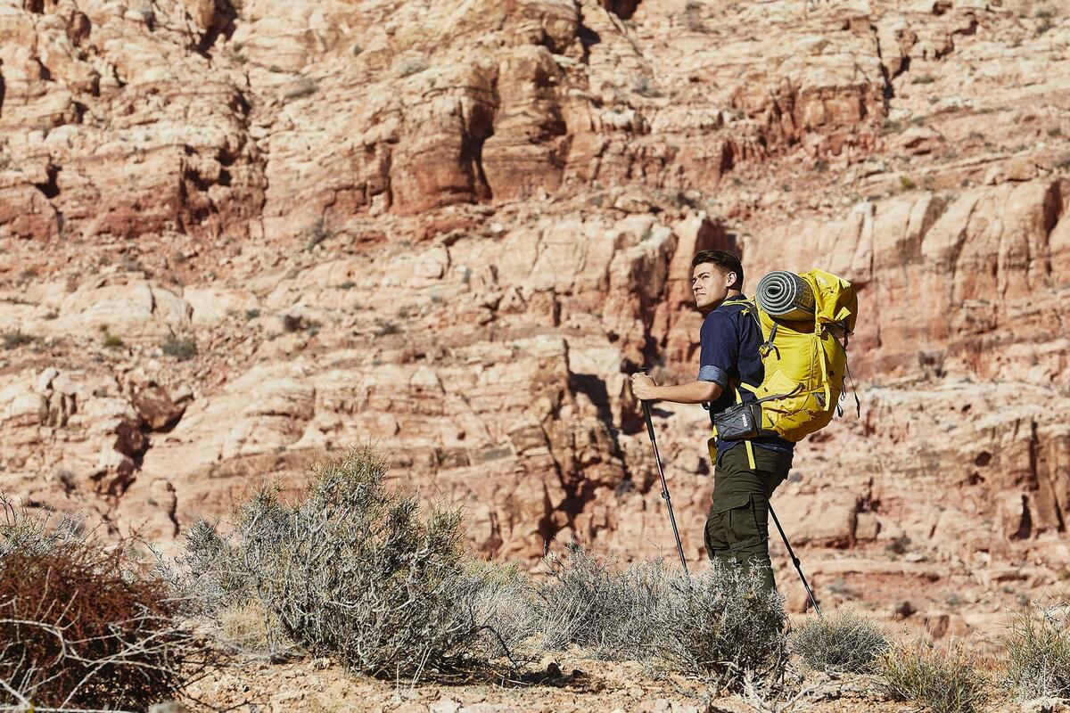 A man with backcountry equipment hiking near red rock.