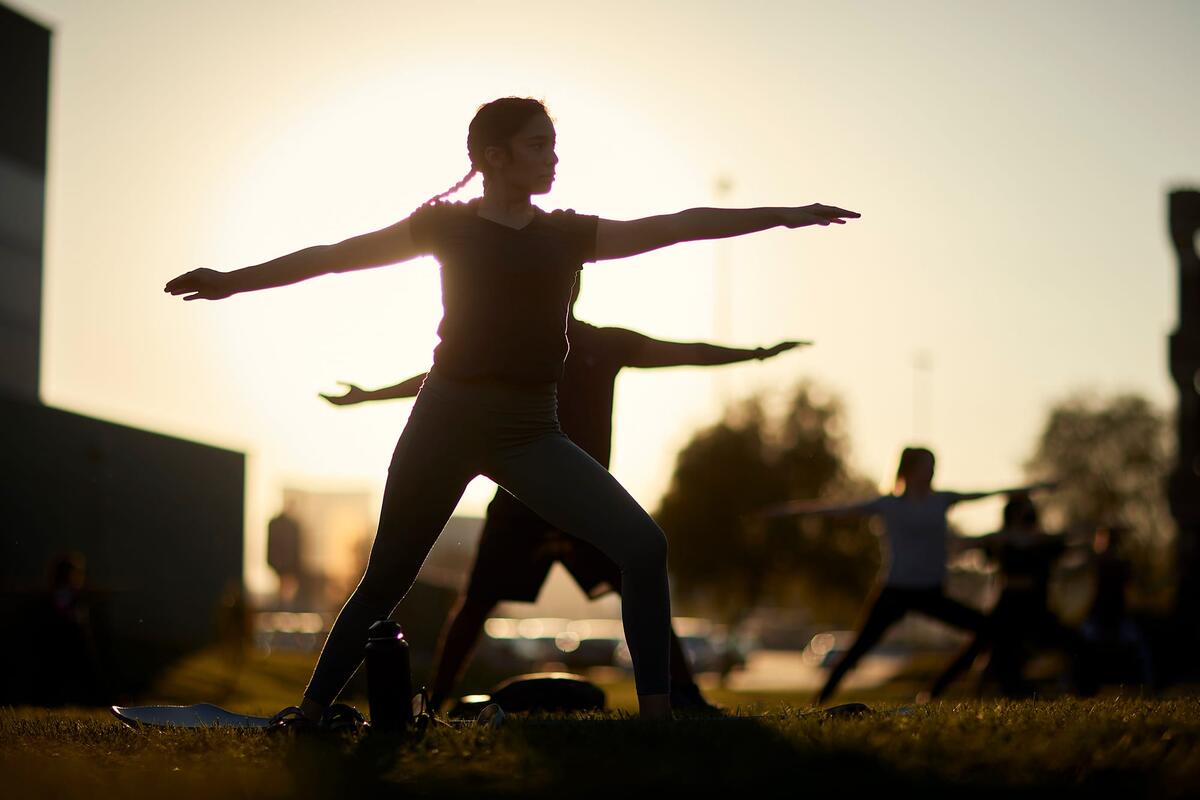 Students perform yogoa outside suring sunset