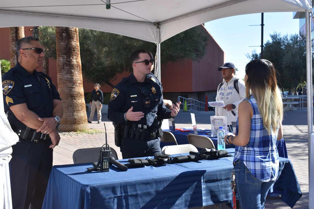 Two officers at booth speak to student