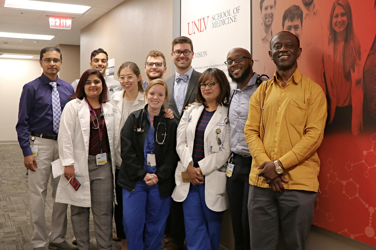 A group of people, some in white coats with stethoscopes around their necks, are posing for a picture.