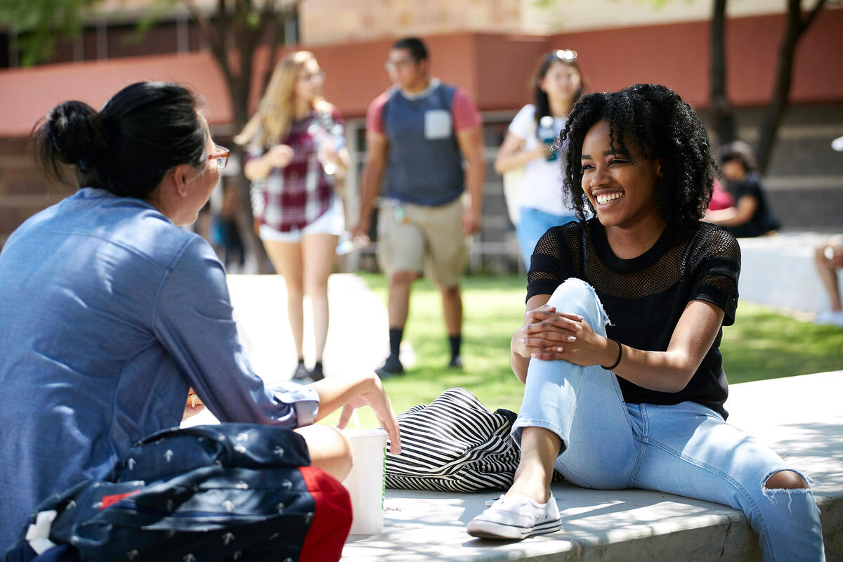 Two students sitting and conversing on campus.