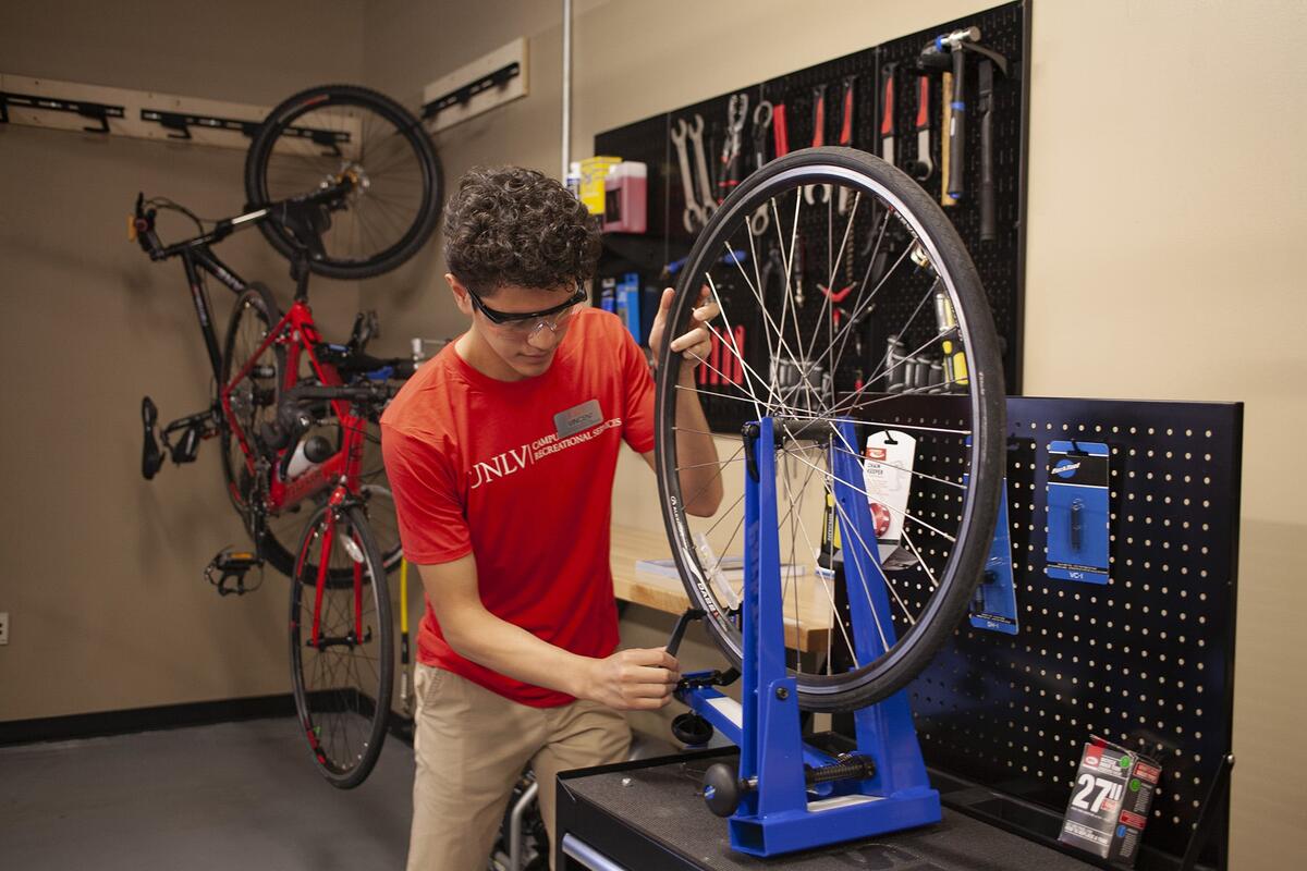 A maintenance worker repairing the wheel of a bike.