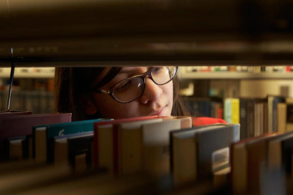 A student searching for a book in the library.