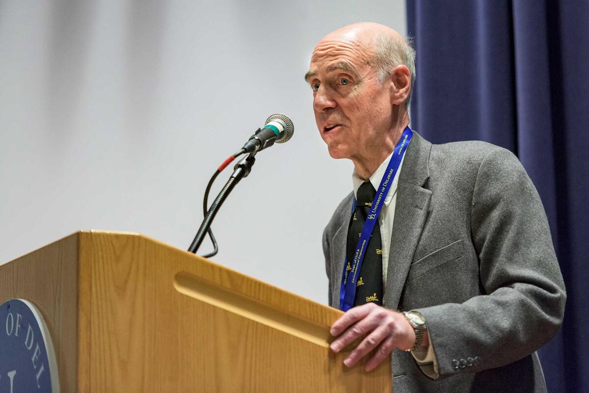 Man in a suit speaking behind a wooden podium
