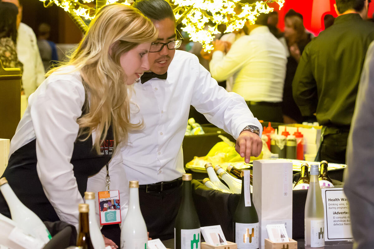 Two students at a hospitality event setting up a table.