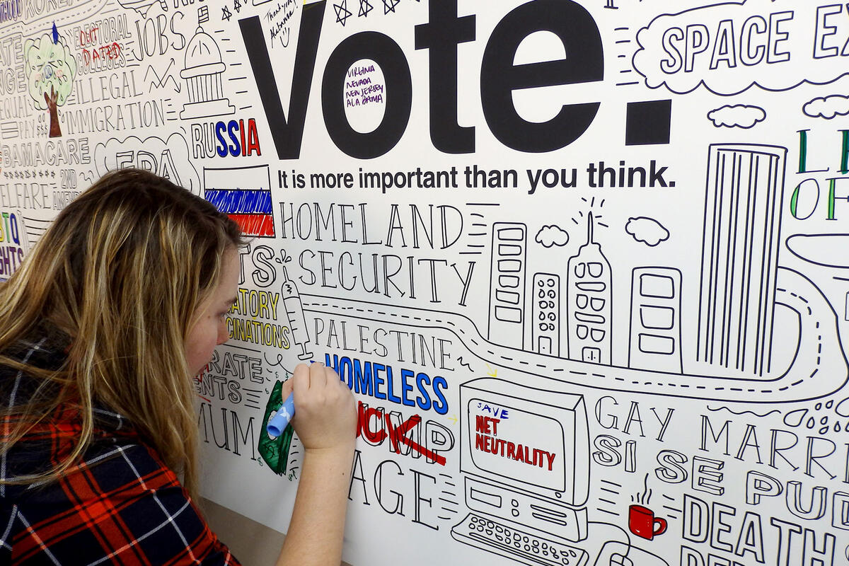 Student using a marker to color an infographic about voting