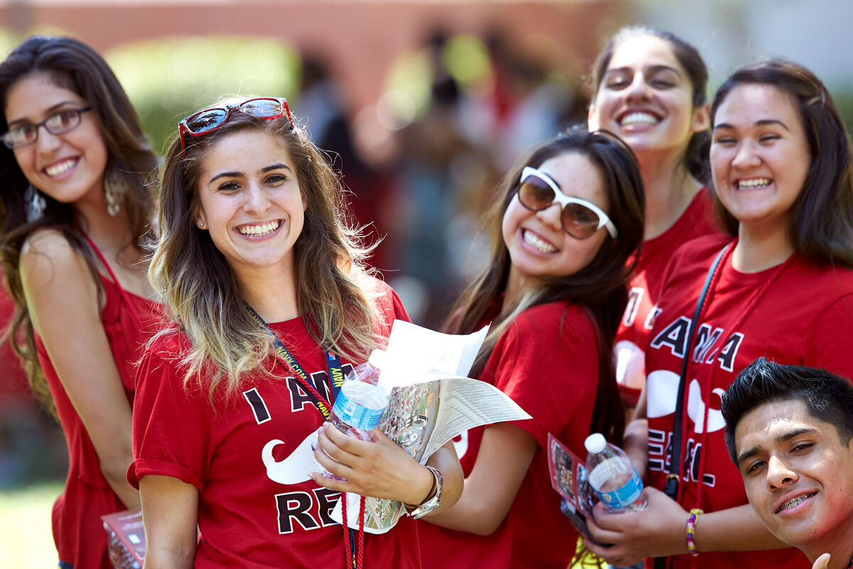 A group of female students wearing rebel red and smiling for the camera.