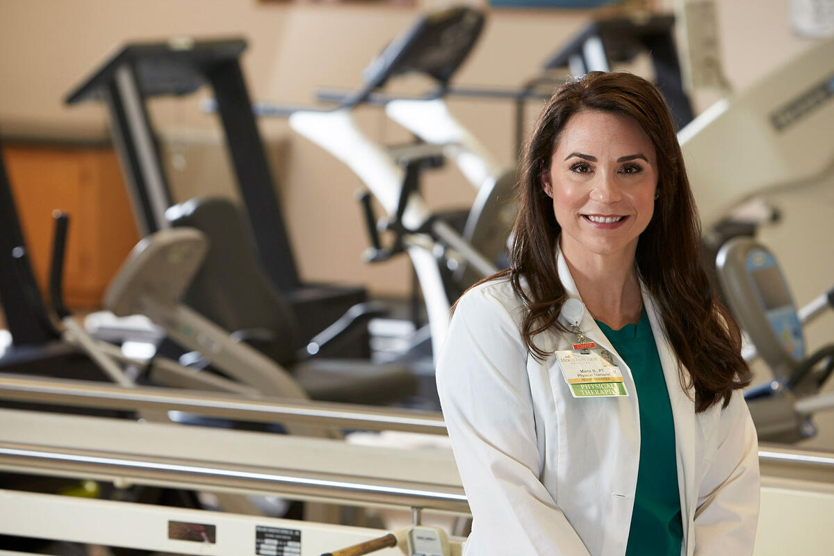 Female in white lab coat standing in front of various training machines