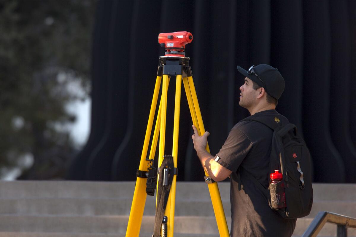 Student uses surveying equipment on campus