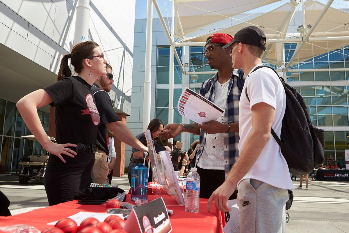 Students talking to a woman at a booth