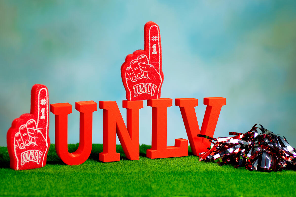Miniature UNLV sign and foam fingers on a grass turf backdrop