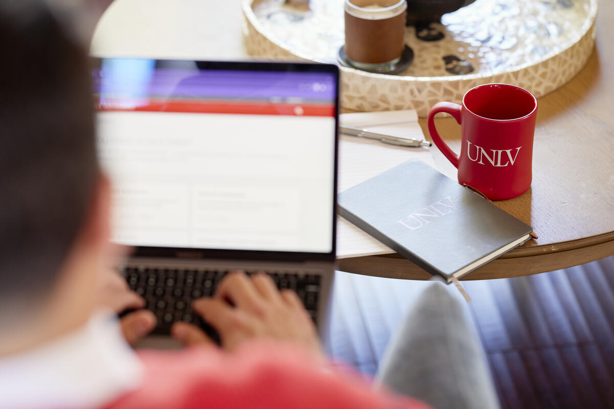 a person with a screen and UNLV red mug