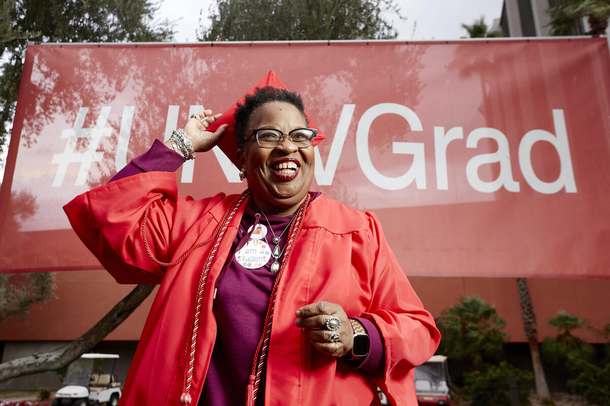 Beverly Jackson smiles as she stands tall in red graduation gown.
