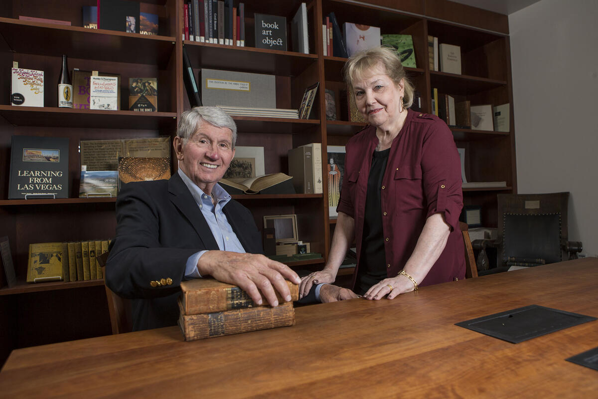 couple at desk with bookcases behind them