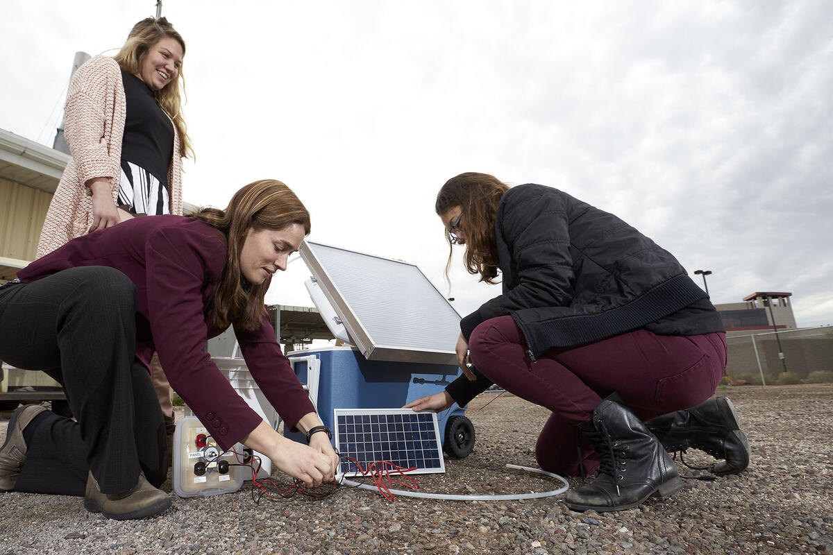 professor works with two students on solar kit