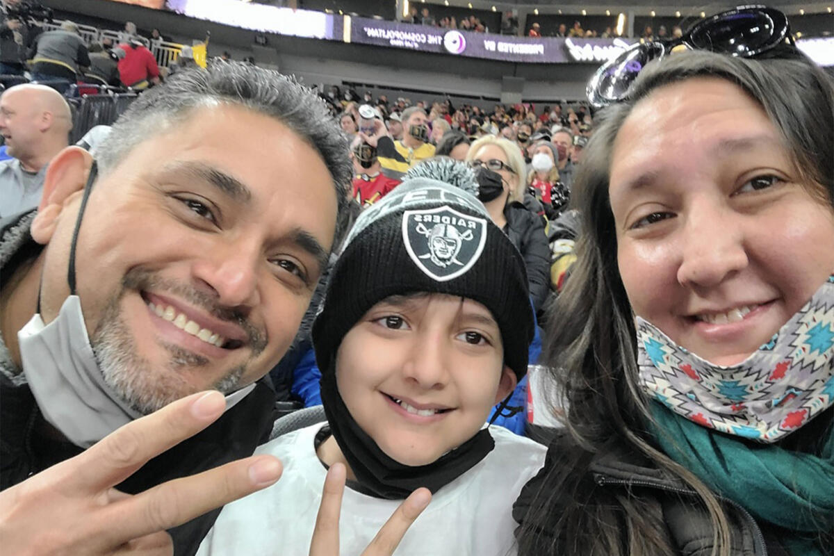 woman, man and child in the stands at Raiders football game