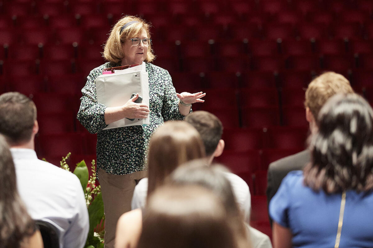 woman with clipboard talking to group of students