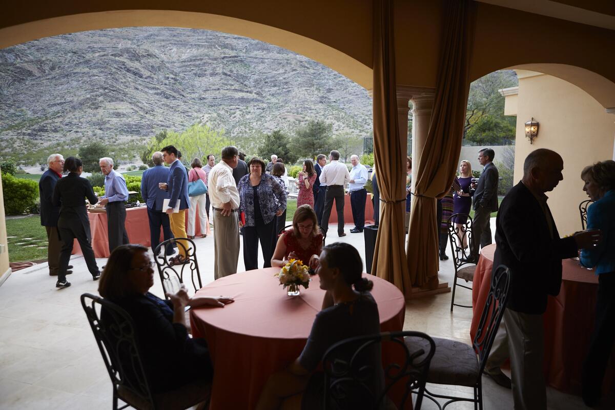 A gathering of alumni, donors, parents, and friend at tables and outdoors at a local event
