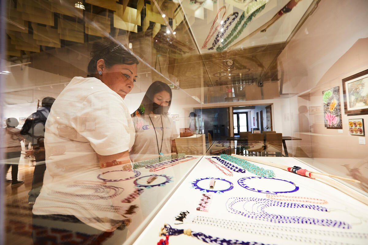 a woman and girl viewing Native American jewelry in museum case