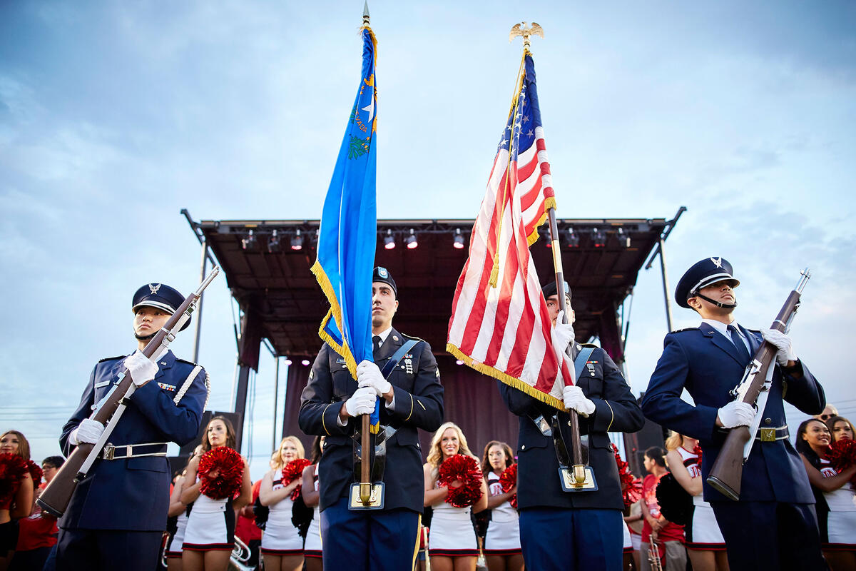 A group of military uniformed men holding the Nevada flag and the US flag