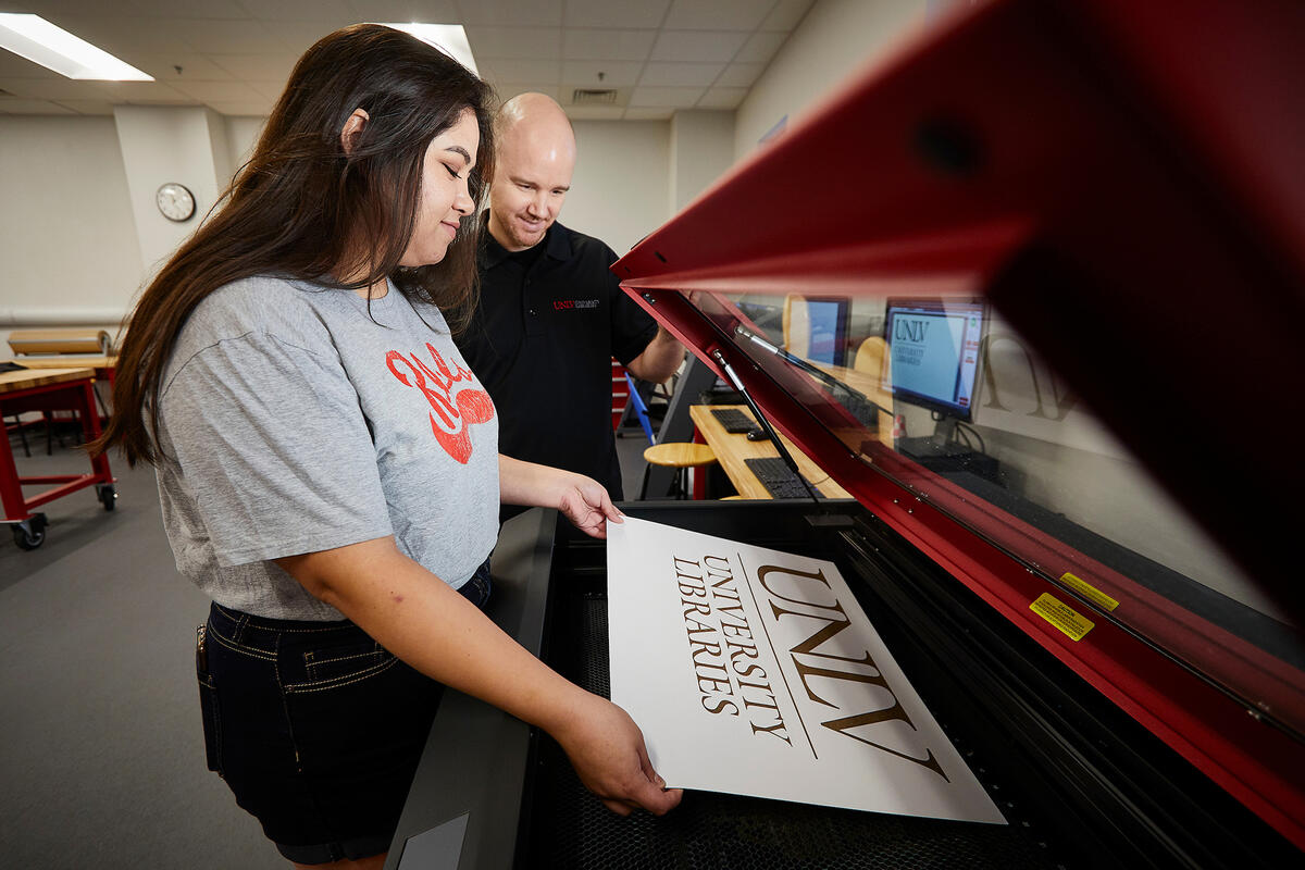 Student and advisor using an engraving machine to create a U.N.L.V. Libraries sign