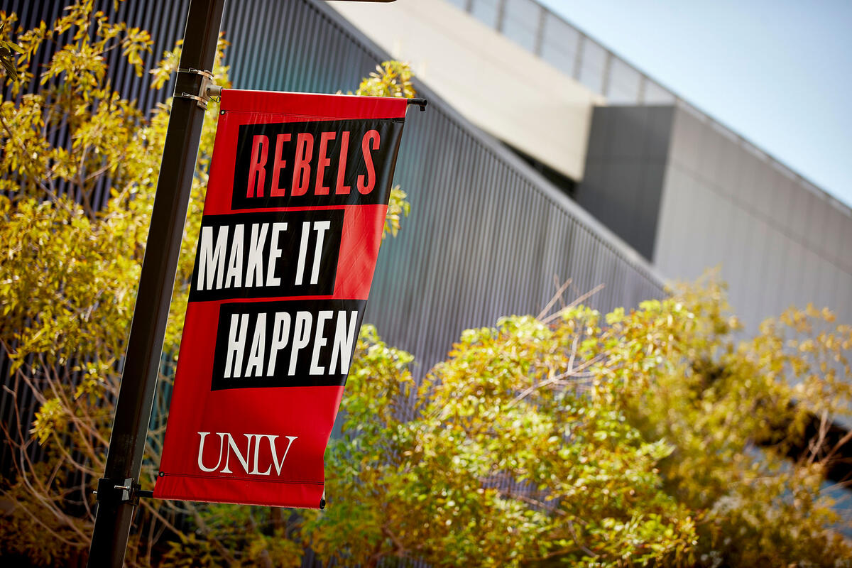 Rebels Make It Happen branded statement on signage with the U-N-L-V brand at its base, on campus.